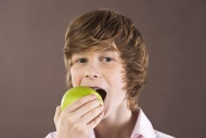 Boy biting a green apple