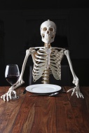 Skeleton sitting at a laid ta...