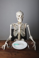 Skeleton sitting at a laid ta...