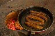 Sausages frying in a pan on a...