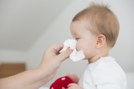 Mother blowing baby girl\'s nose