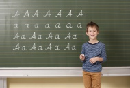 Schoolboy at blackboard writi...