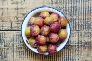 Enamel bowl of plums on wood