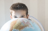 Little boy hiding behind a globe