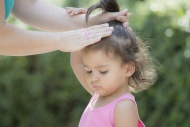 Mother tying hair of her litt...