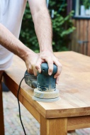 Man sanding an oak table with...