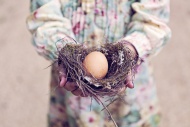 Girl holding an egg in a nest
