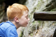 Boy drinking water from a runlet