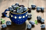 Plums on wood and in blue jar