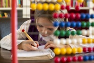 Girl sitting behind abacus do...