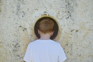 Boy peeking through hole in wall
