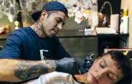 Woman receiving tattoo in tat...