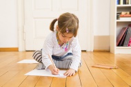 Little girl sitting on wooden...