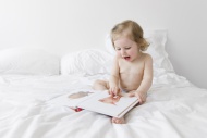 Toddler sitting on a white be...