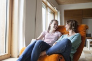 Happy mother and daughter sit...