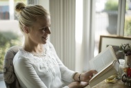 Smiling young woman reading a...