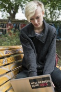 Young woman sitting on park b...