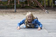 Girl (10) lies on skateboard,...