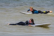 Female surfer in wetsuit lyin...