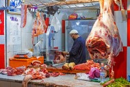 Butcher cutting meat in butch...